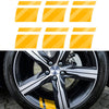 A close-up of a black alloy wheel with yellow and black accents, featuring a pattern of reflective safety stickers.