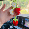 Main tenant un pendentif-clés de fraise crochet fait main avec des accents de fleurs blanches.
