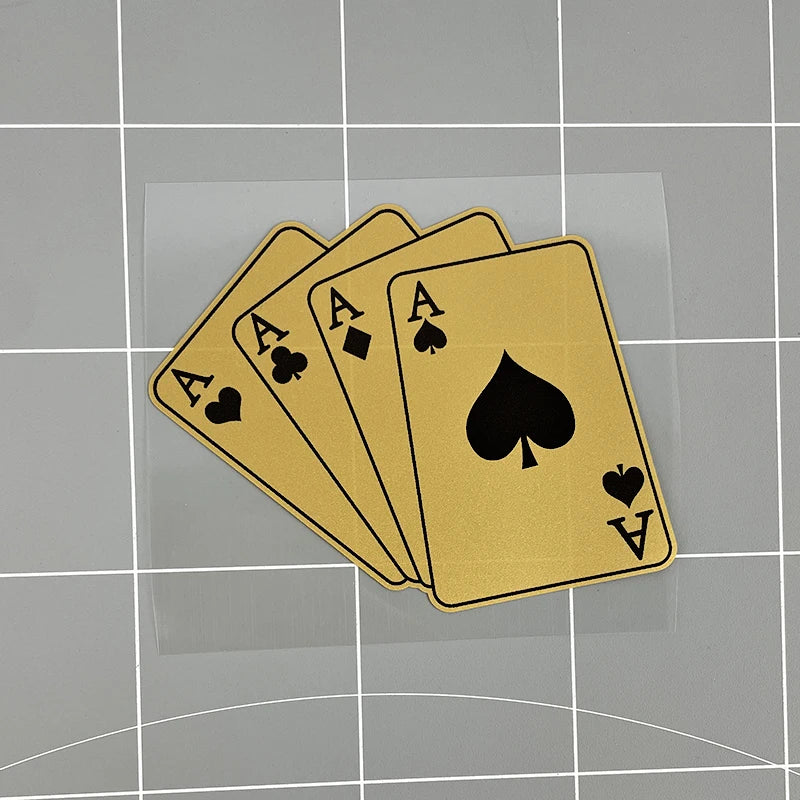 A stack of gold poker playing cards featuring aces and a heart on a transparent sheet.