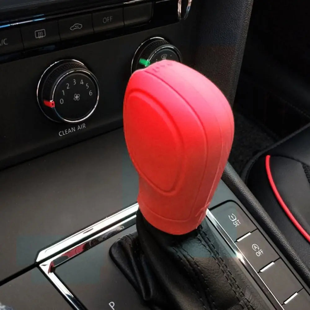 Tapa de palanca de cambios de silicona roja apoyada en la consola interior de un coche.