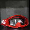 A pair of bright orange motocross goggles with a red frame and clear lenses resting on a dark surface.