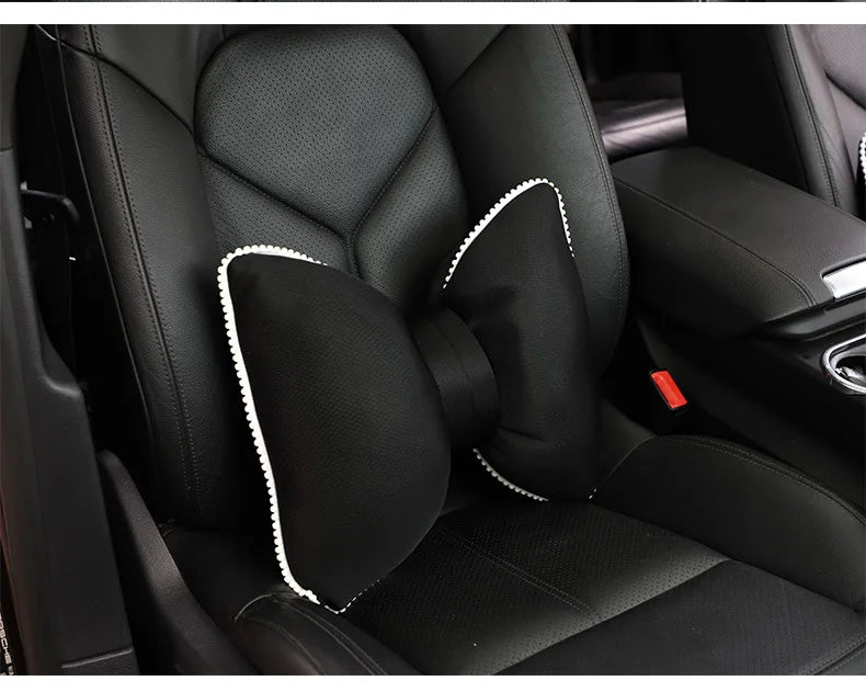 Black ergonomic car headrest pillow with a bow design shown inside a car seat.