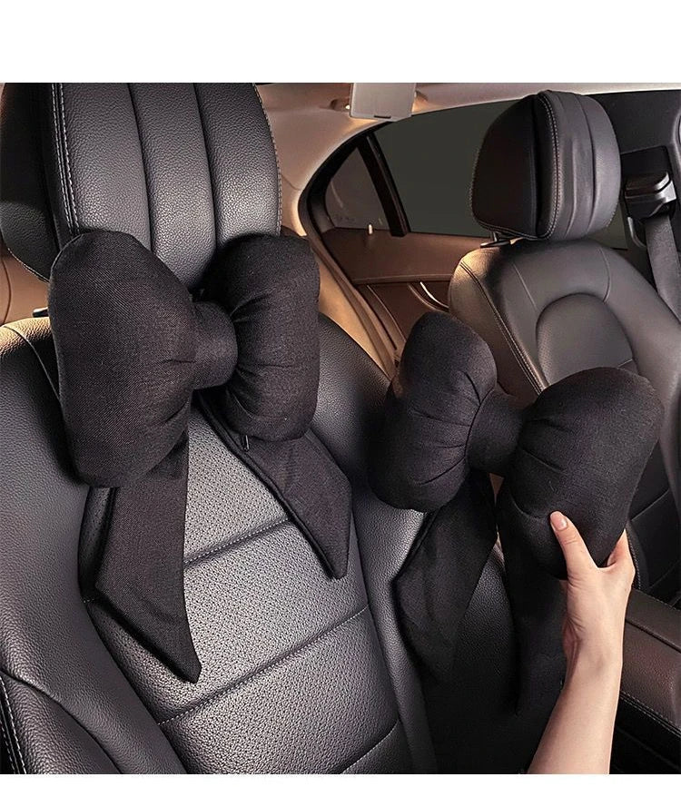Oreiller de cou noir en forme de papillon pour soutien de la tête sur siège de voiture.