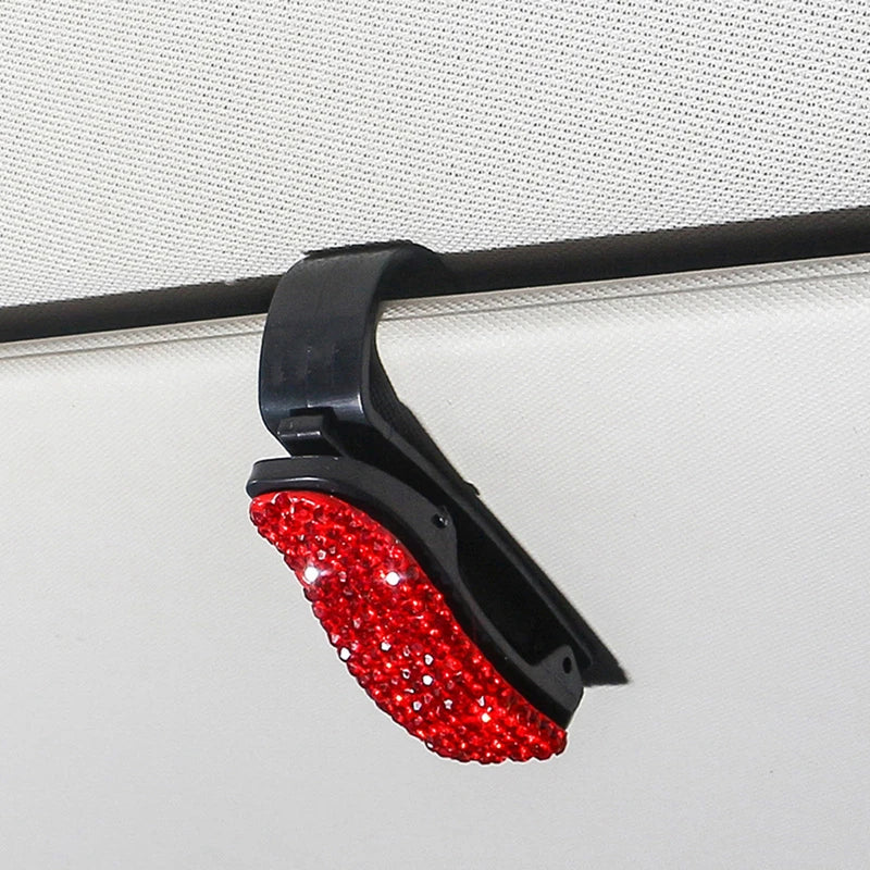 Schwarzer Halter für Sonnenbrillen mit rotem Kristallakzent, montiert auf einer weißen Oberfläche.
