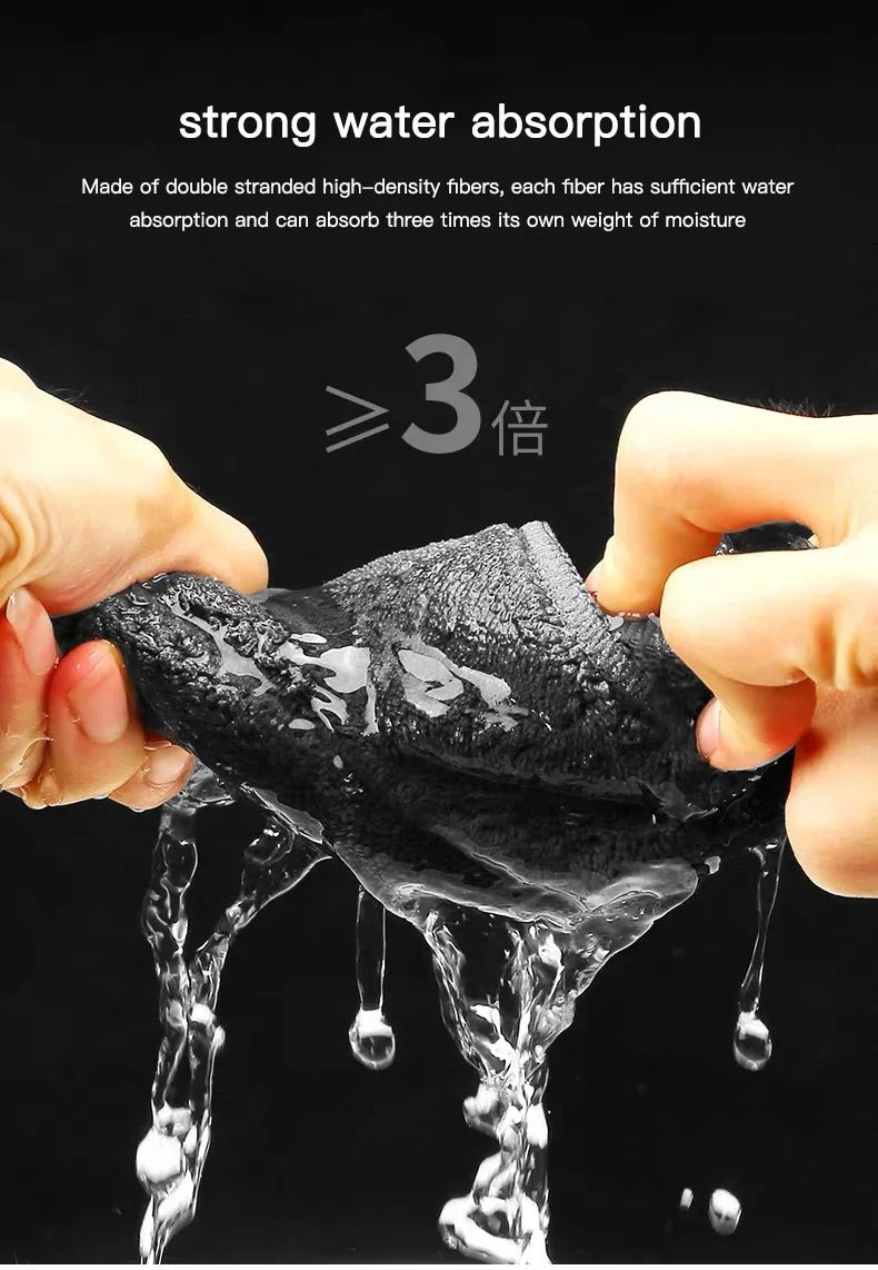 Mains tenant une serviette en microfibre noire, démontrant une forte absorption d'eau par des gouttes.