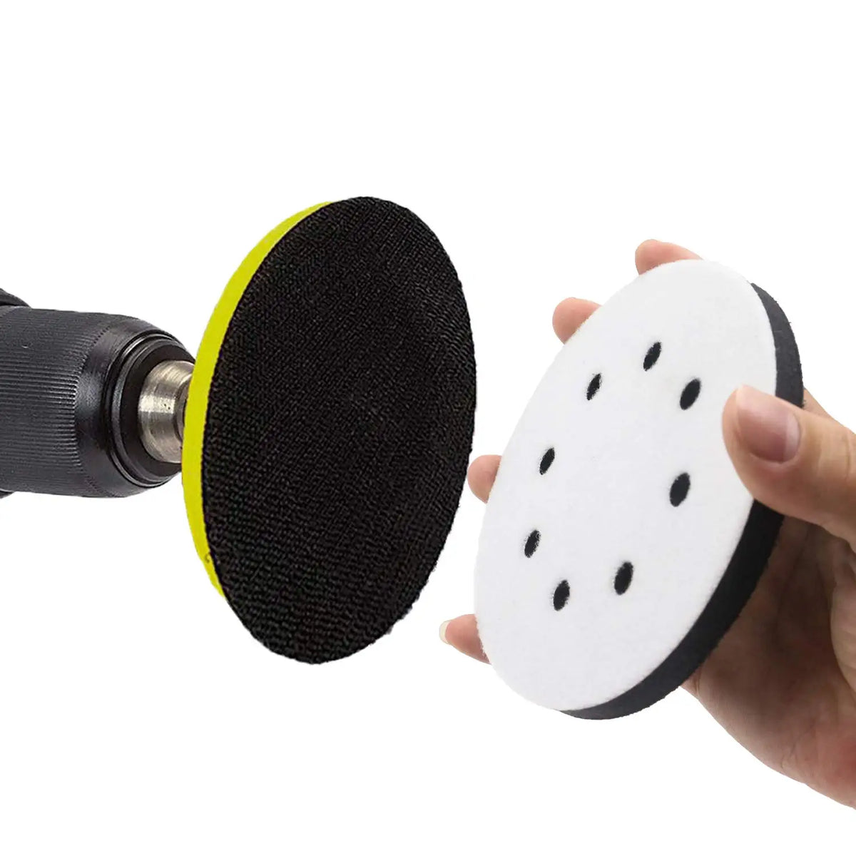 A hand holds a black sanding pad with a yellow rim and a white abrasive interface pad featuring black dots.