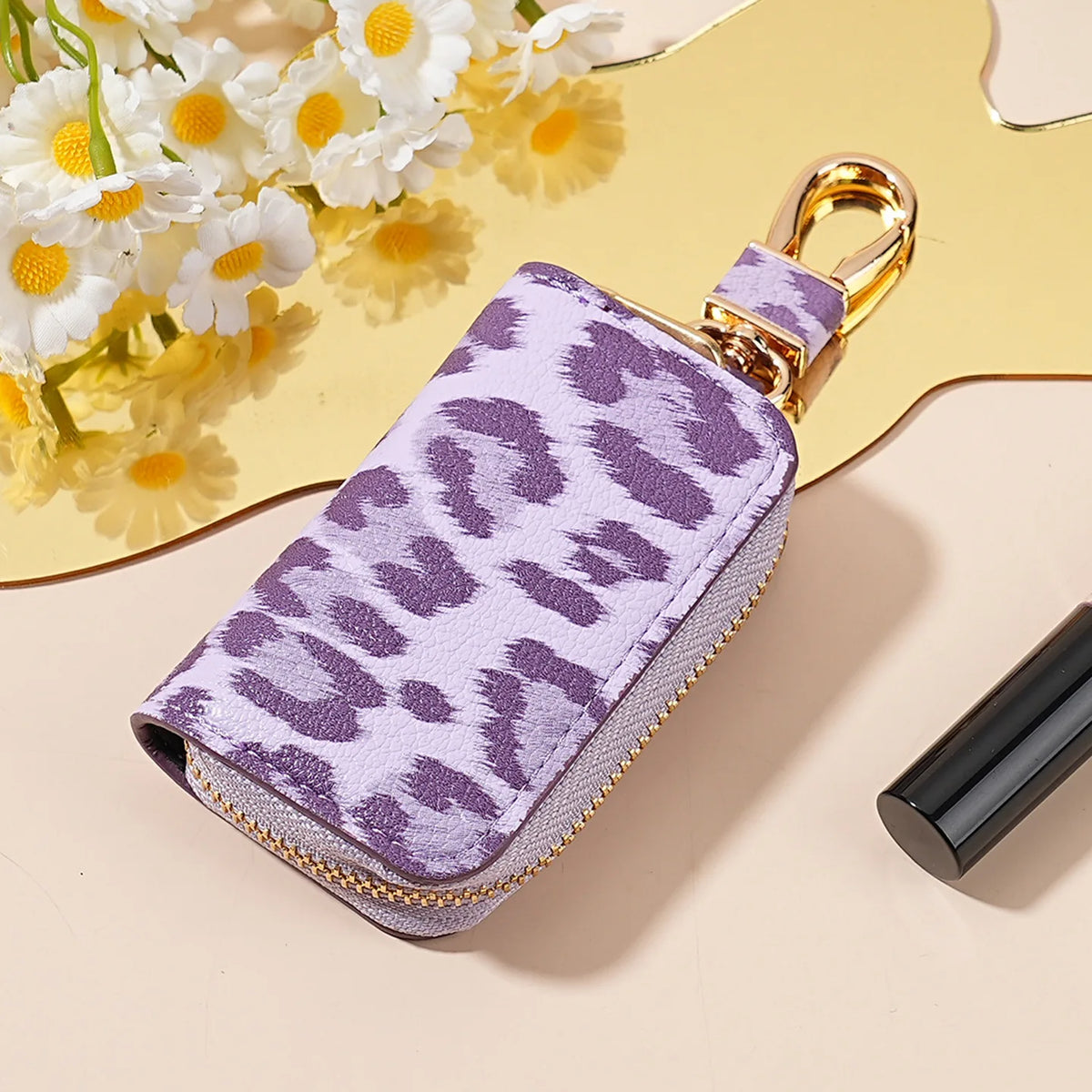 A purple leopard print car key holder with a gold clasp resting on a light background.