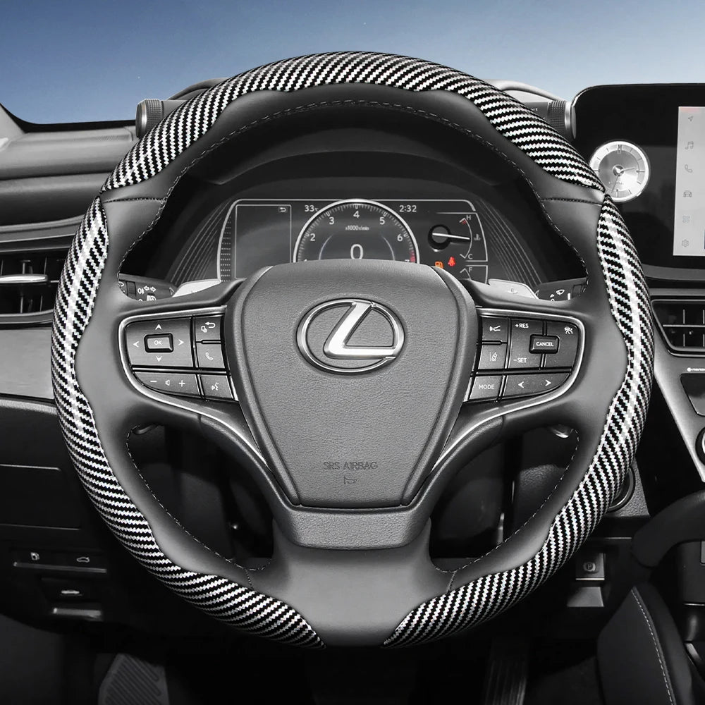 Close-up view of a Lexus steering wheel with black leather grips and a patterned carbon fiber trim.