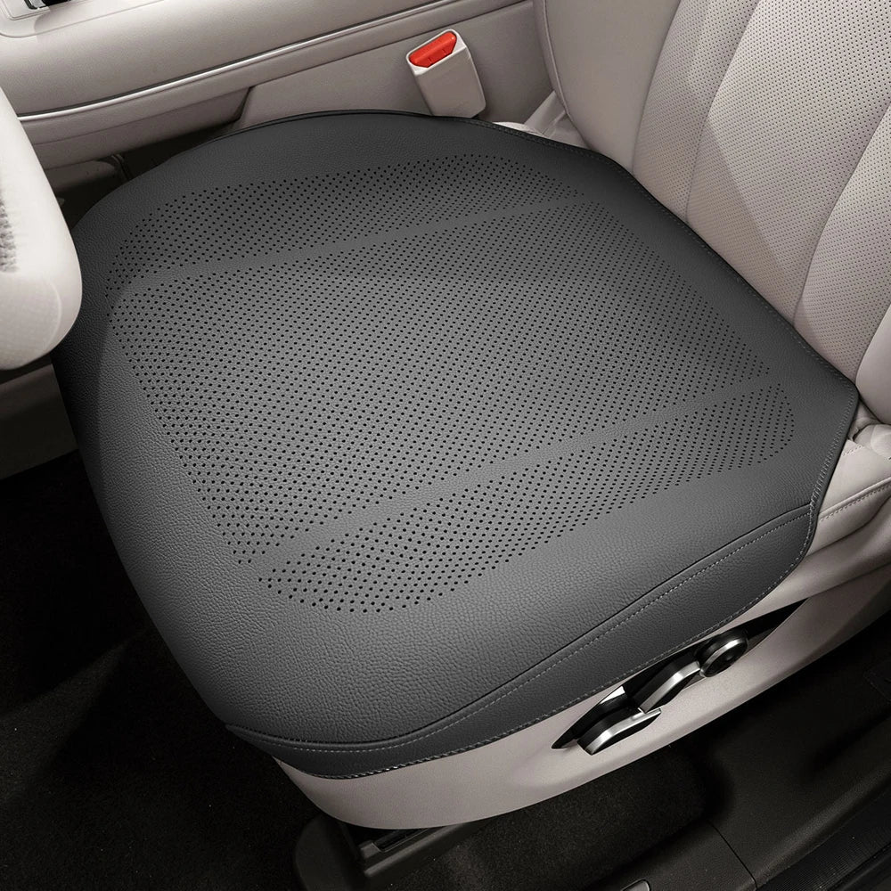 A gray breathable car seat cushion is shown in the interior of a vehicle.