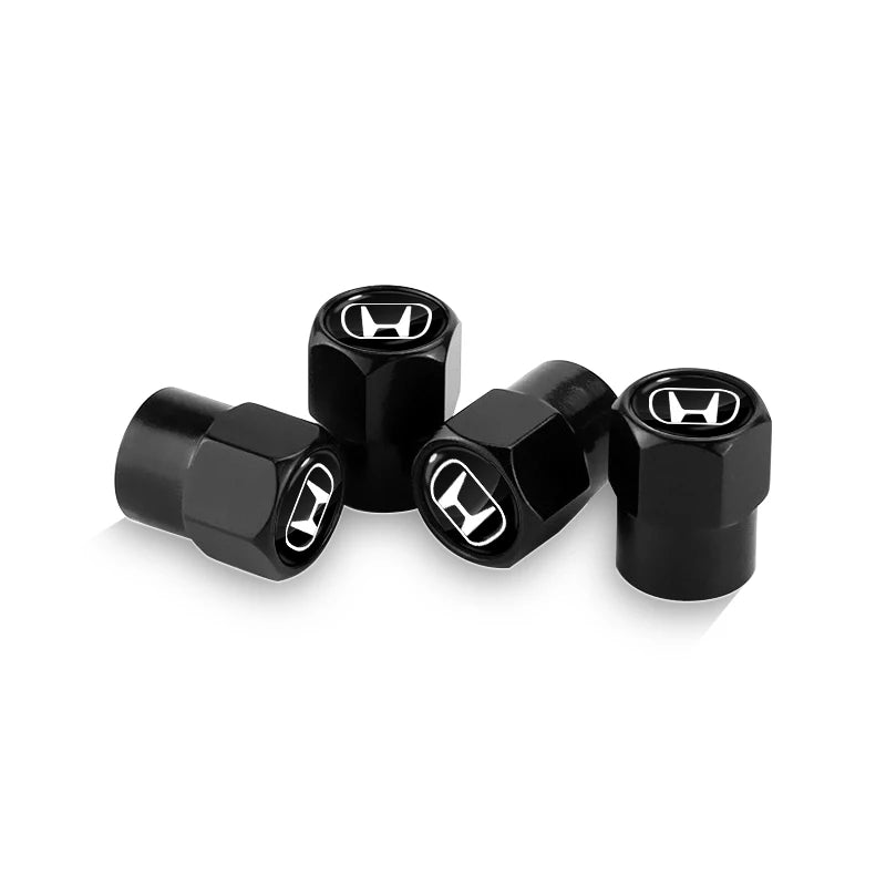 A set of four black anodized tire valve caps for automotive use.