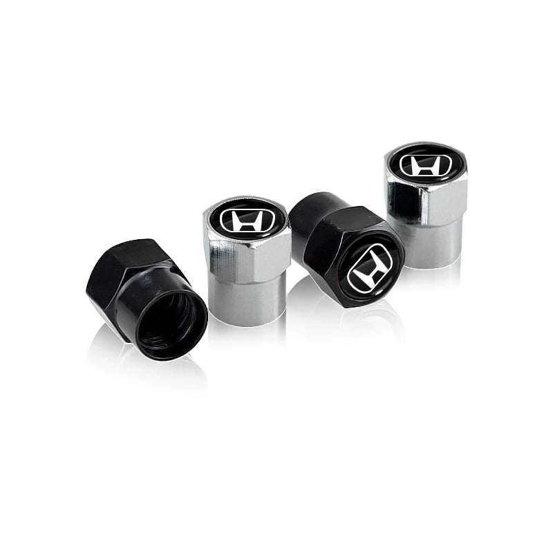 A set of four metal and black anodized tire valve caps for automotive use.