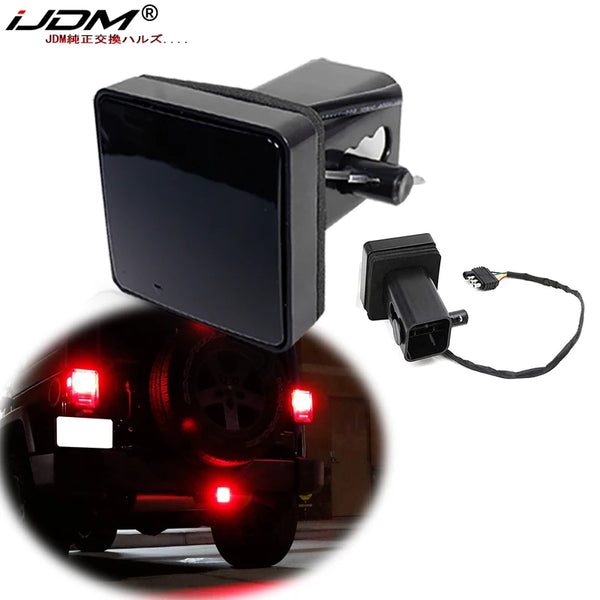 Una cubierta de luz de freno LED negra para un enganche de remolque junto a una agrupación de luces traseras automotrices.