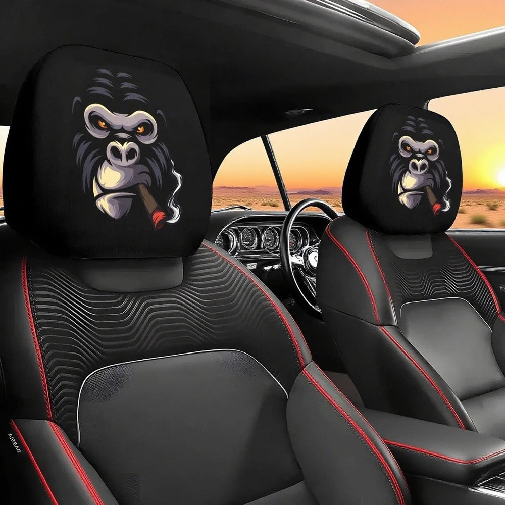 Two black car headrest covers featuring stylized, funny slanted eyes monkeys on a black leather interior.