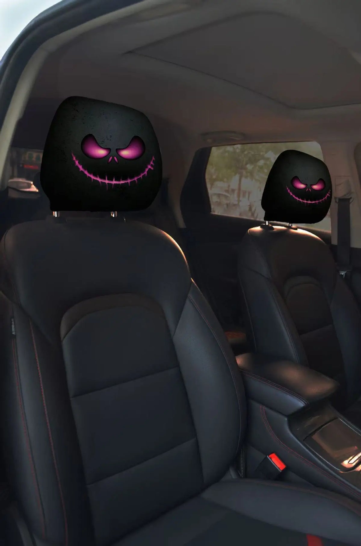 Two black horror-themed car headrest covers with glowing purple smiles installed in a vehicle interior.
