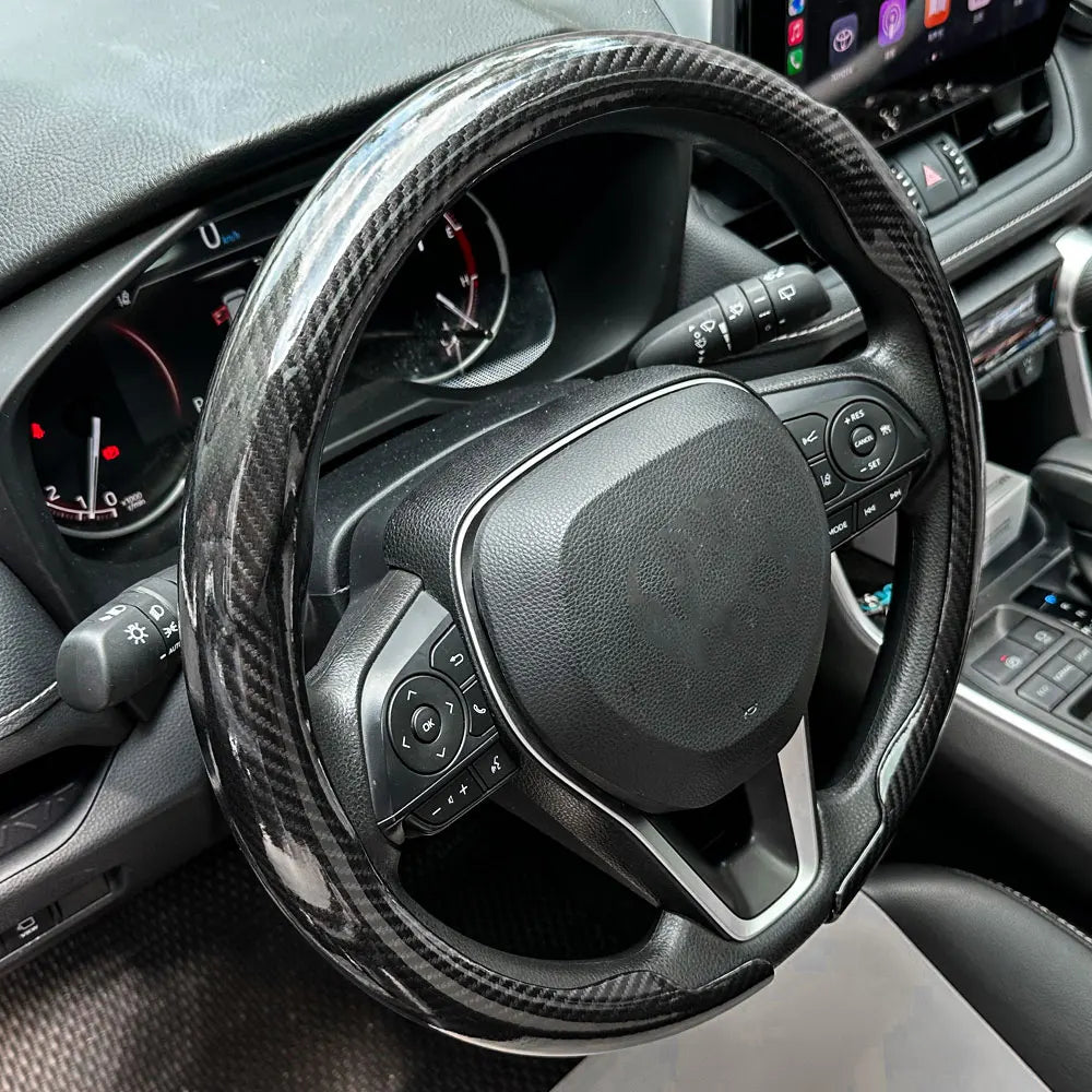 Nahaufnahme einer schwarzen Kohlefaser-Lenkradabdeckung im Auto-Innenraum.