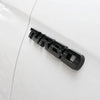 Black three-dimensional metal alloy turbo badge mounted on a white car body.