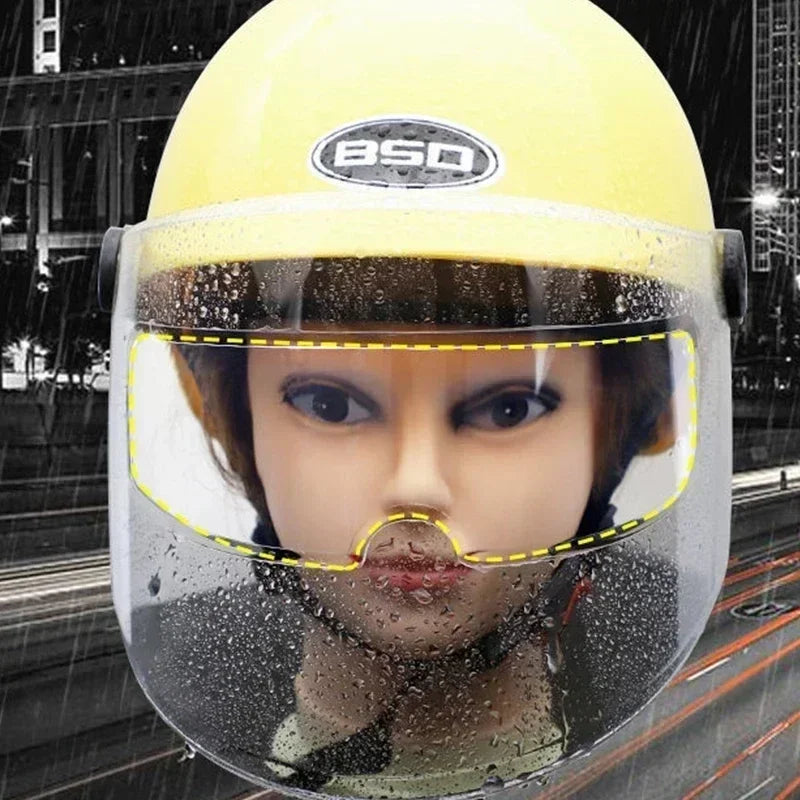 A yellow motorcycle helmet visor is covered in water droplets, showing a close-up view of the face.