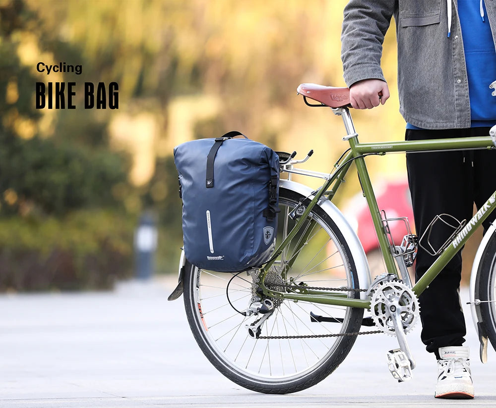 A person is carrying a blue bike bag on a green bicycle outdoors.