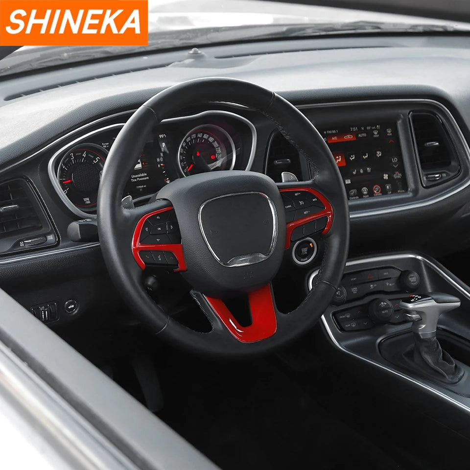 Interior view of a car steering wheel with a black cover featuring red accents and digital displays.