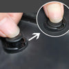 Close-up of a hand pressing a plastic rivet or push pin fastener on a black surface.