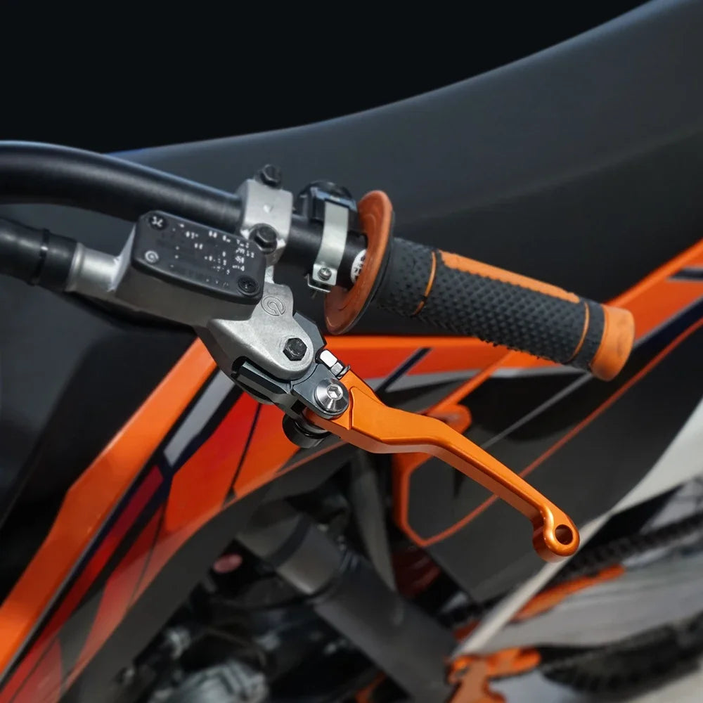 Close-up of precision aluminum brake and clutch levers on an orange off-road bike handlebar.