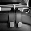 Close-up of black car seat headrest hooks with silver accents for vehicle organization.