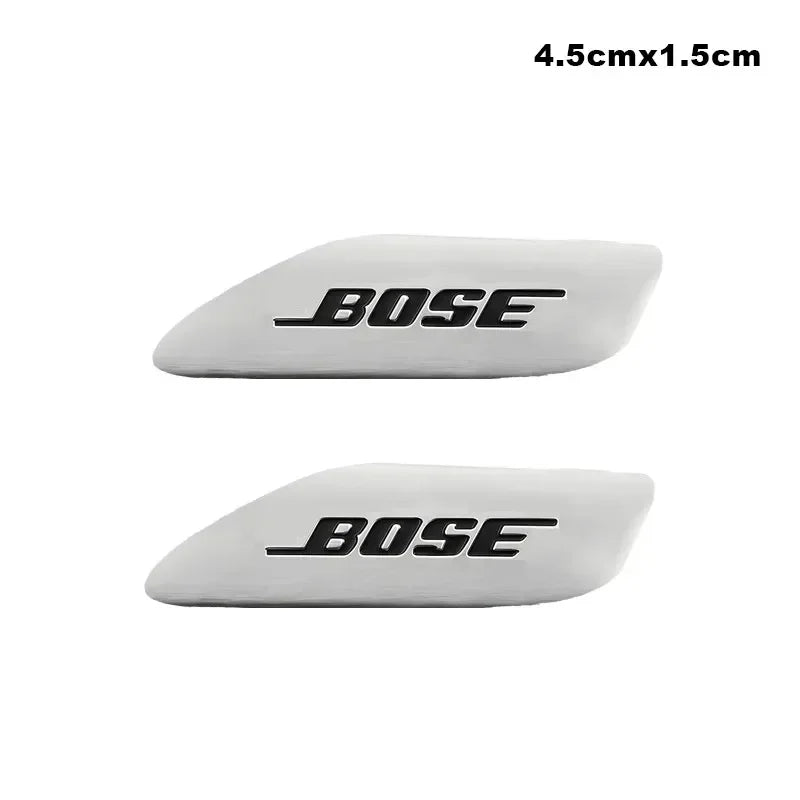 Two white Bose car audio emblems, measuring 4.5cm by 1.5cm.