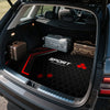 Interior view of an SUV trunk with a black floor mat and several luggage pieces.