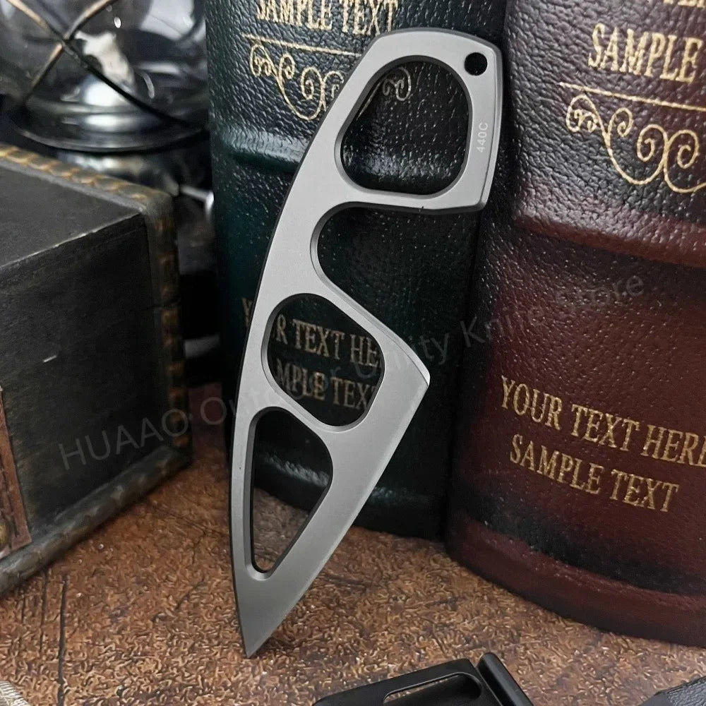 A silver fixed blade survival knife is shown against a dark background with other items.