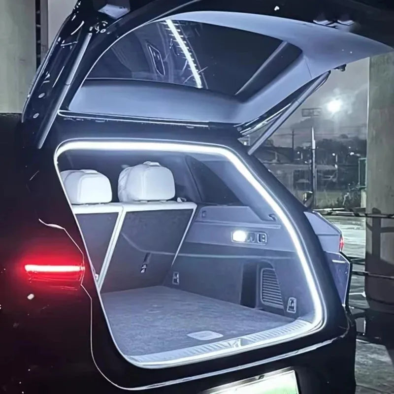 Vue intérieure du coffre d'une voiture avec une bande lumineuse LED éclairant l'espace de rangement.