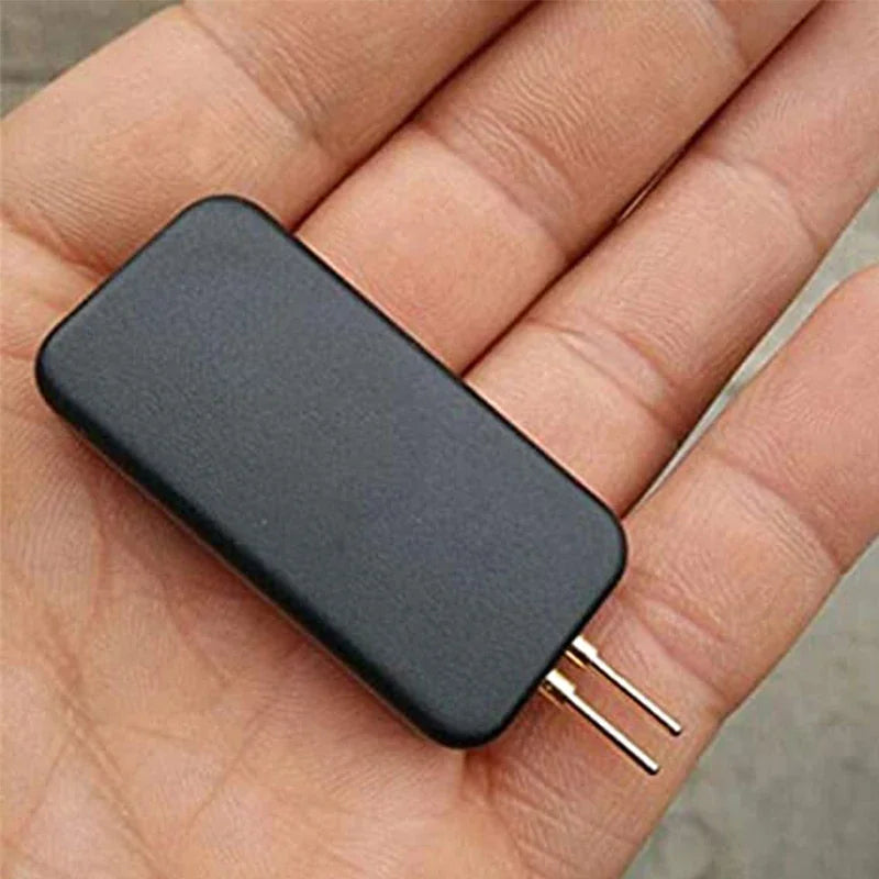 A black electronic device with two gold-tipped probes is held in a person's hand.