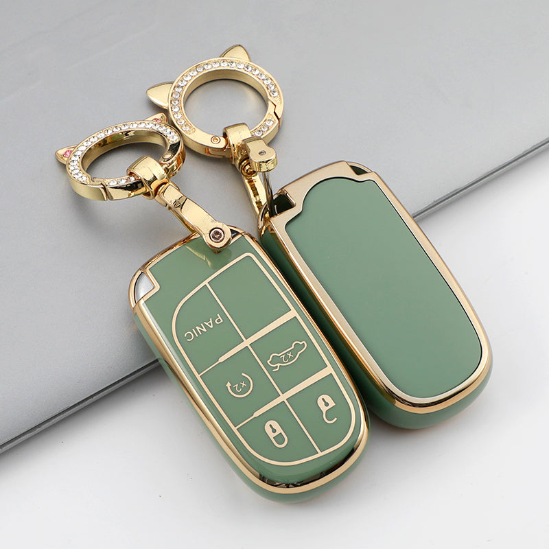 A gold-toned TPU car key case cover with a green insert and a keyring is shown on a gray surface.
