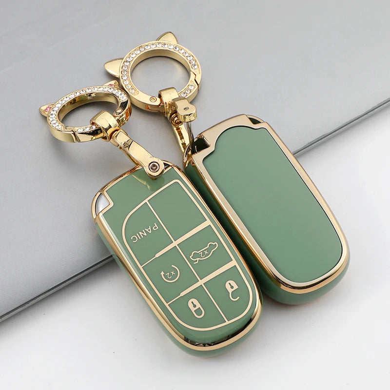 A gold-toned TPU car key case cover with a green insert and a keyring is shown on a gray surface.
