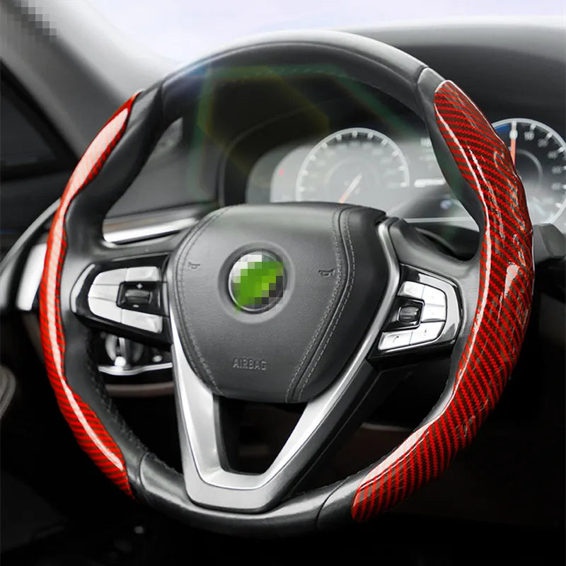 Gros plan d'un volant noir recouvert de protections en fibre de carbone rouge.
