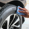 A hand is using a blue microfiber pad to polish the rim of a car wheel.