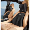 A black ergonomic lumbar support pillow is shown installed in the seat of a car, designed for travel.