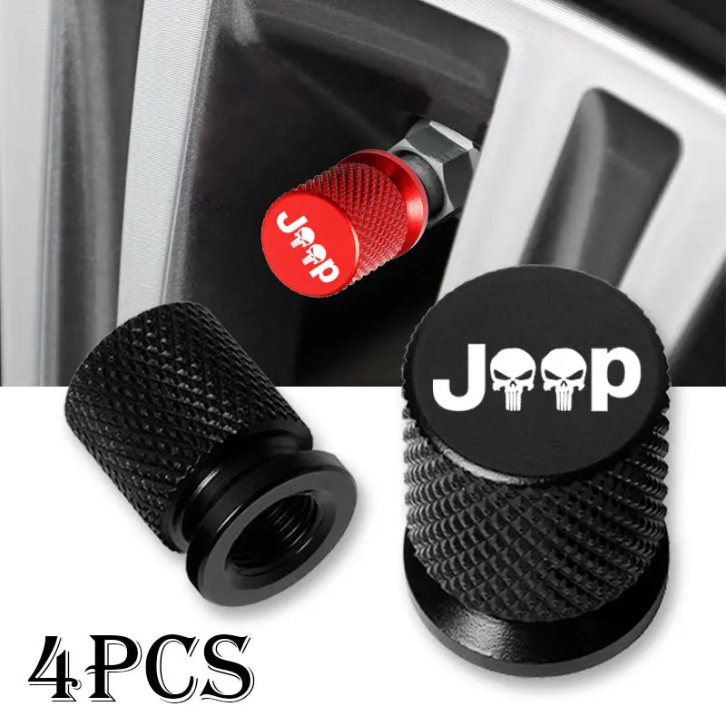 Four black tire valve caps with red accents shown next to a car wheel assembly.