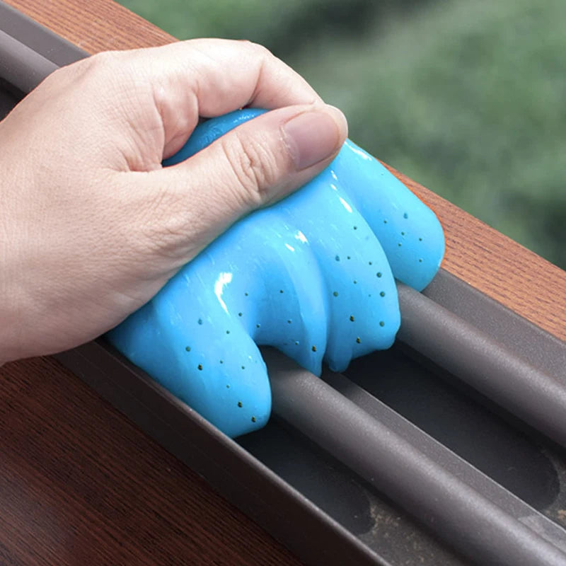 A hand is squeezing a bright blue magic gel cleaner onto a dark wooden surface.