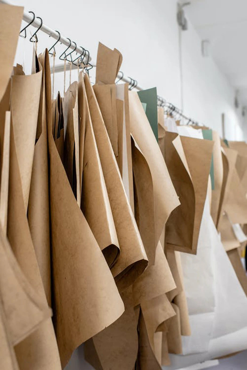 A rack of tan and beige fabric car seat covers hanging on a metal hanger.