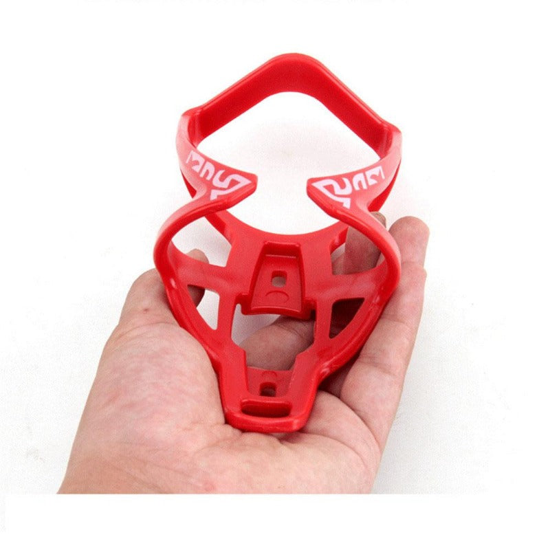 A bright red plastic bicycle bottle holder rack is shown being held in a hand.