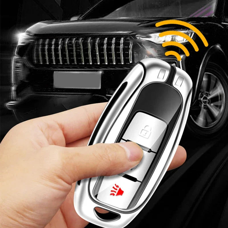 A hand holds a silver car key cover with a fingerprint scanner, positioned near a black car.