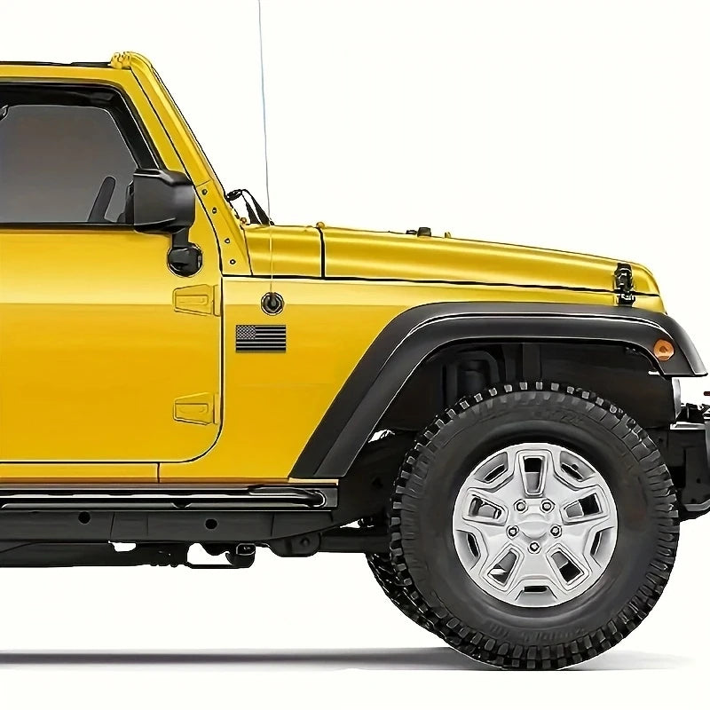 A yellow Jeep Wrangler with matte black 3D American flag decals and off-road tires.