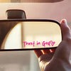 A hand holds a faith heart vinyl decal displaying the text Trust in God with a heart symbol.