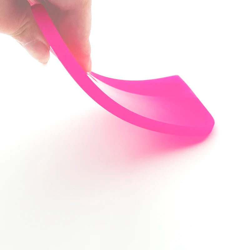 A hand is holding a bright pink anti-scratch PPF squeegee, demonstrating its use for window tinting or film installation.