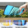 A hand holds a curved blue motorcycle helmet visor showing different light conditions, including evening and sunlight.
