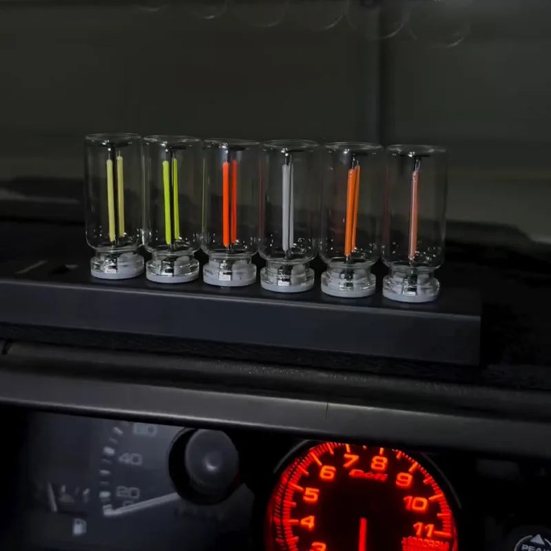 A row of glass tubes containing various colored LEDs, including yellow, green, orange, and red, resting on a dark surface.