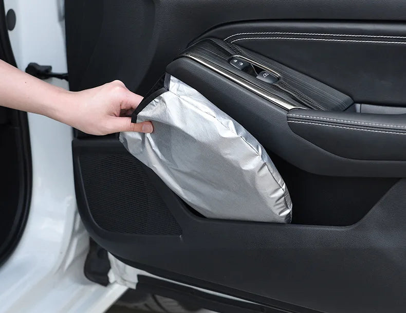 Une main ouvre un pare-soleil argenté de voiture premium stocké dans le panneau de porte intérieur.