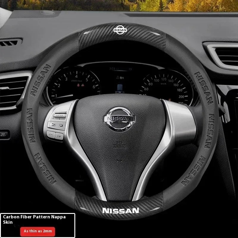 Close-up view of a black Nissan steering wheel with carbon fiber patterned leather grips and controls.