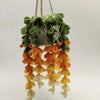 A hanging crochet strawberry decor featuring green, orange, and cream textured fruit shapes.