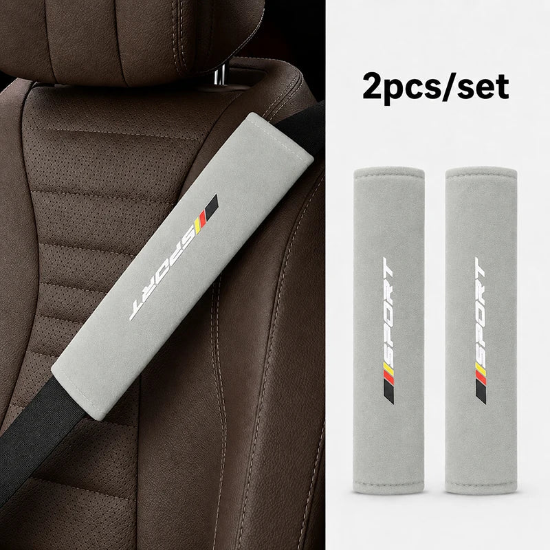 Two gray shoulder pads for a car seat belt set against a brown leather seat.
